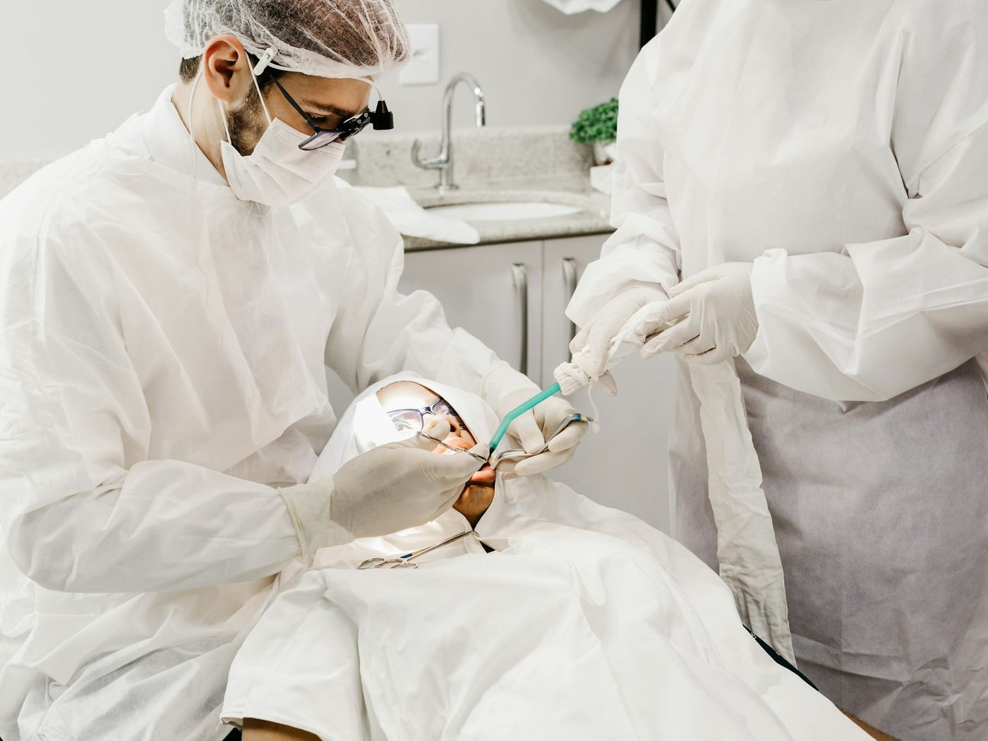 Two clinicians in full protective equipment working carefully on a patient