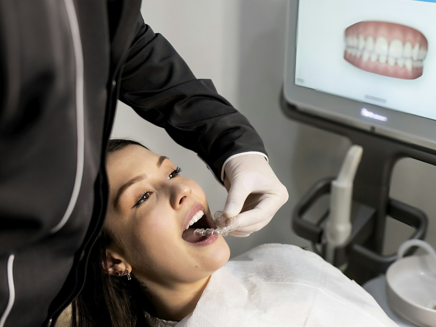 A dentist scanning a patient's teeth digitally, with the 3D model on screen